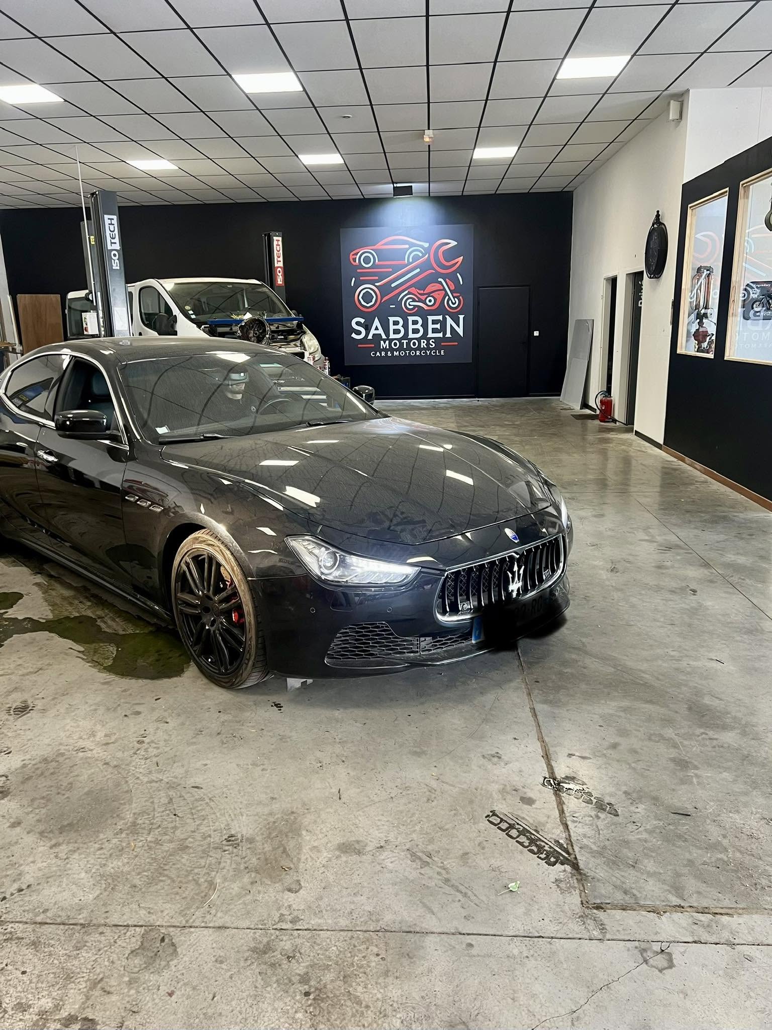 Véhicule pris en charge dans l'atelier Sabben Motors, devant le logo de l'enseigne